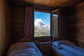 Comfortable guest room with rustic wooden furniture and large windows framing the mountain landscape.