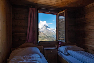 A cozy guest room with traditional Indian decor and a view of Uttarakhand's mountains.