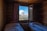 A cozy hotel room with a large window showcasing lush green mountains under a clear sky.