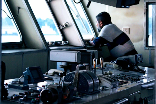 Close-up of a yacht engineer inspecting advanced navigation instruments on a luxury superyacht bridge.