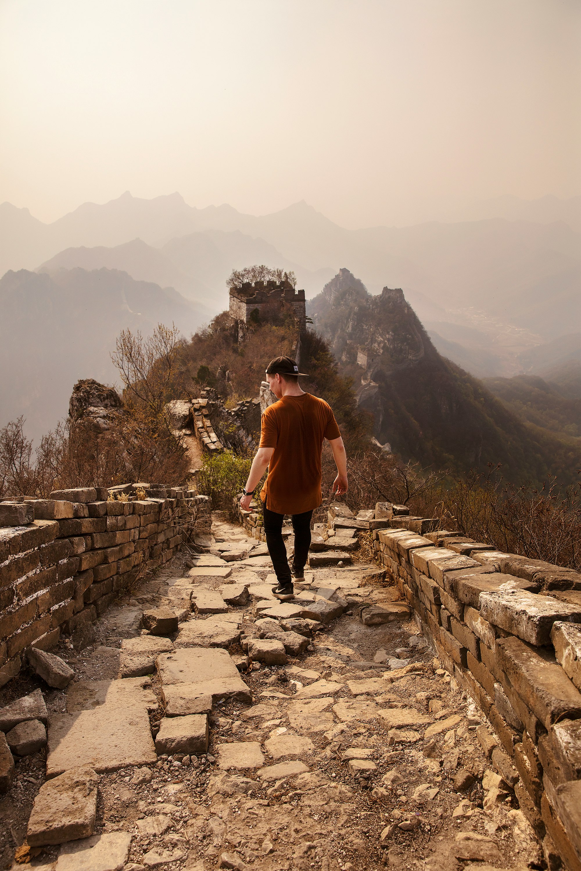 A man walks a wild stretch of the Great Wall of China.