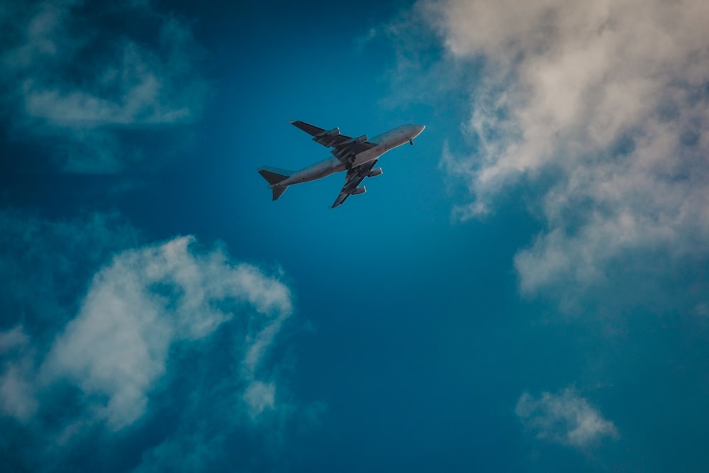 Avión blanco bajo cielo nublado azul y blanco