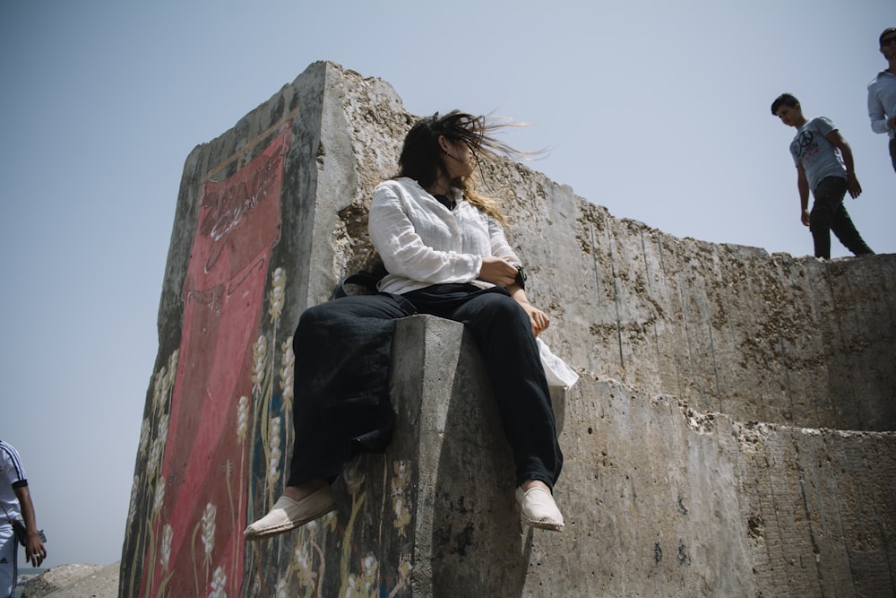 mulher sentada na parede de concreto