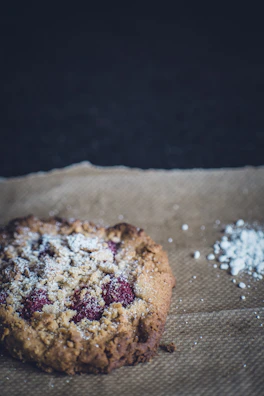 A delicate linzer cookie dusted with powdered sugar, surrounded by cinnamon sticks.