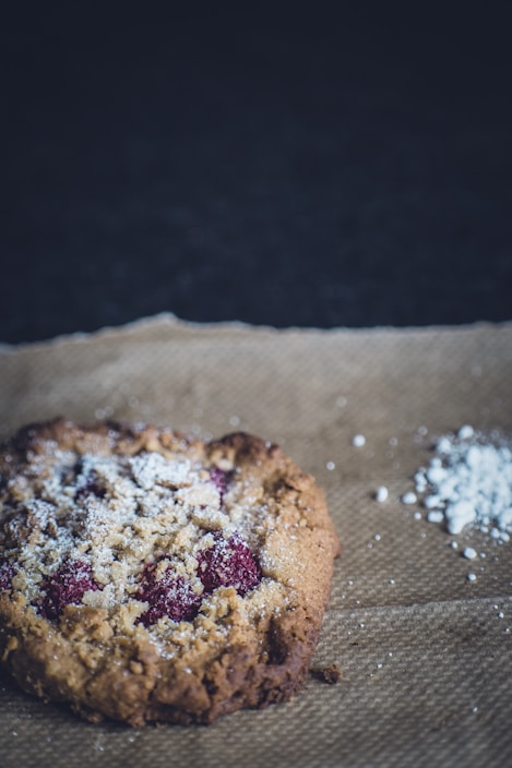 Close-up of golden-brown Pfefferneusse cookies dusted with powdered sugar on a rustic wooden board.