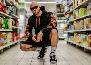 man squatting on floor between grocery items