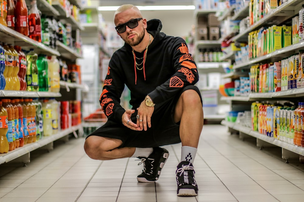 man squatting on floor between grocery items