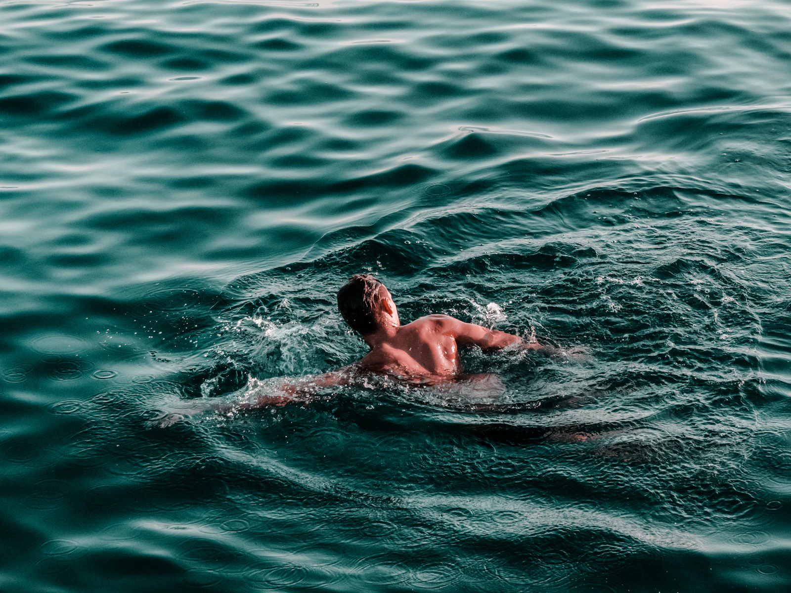 Diver descending into deep blue cold water