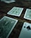 Several playing cards are scattered across a rustic wooden surface. The cards have intricate green designs on their backs, with one card facing up displaying the number five of spades.