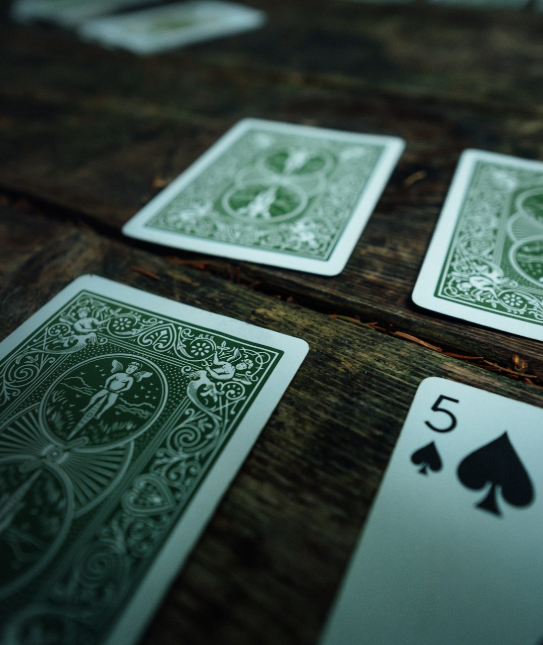 5 of spades playing opened on brown wooden surface