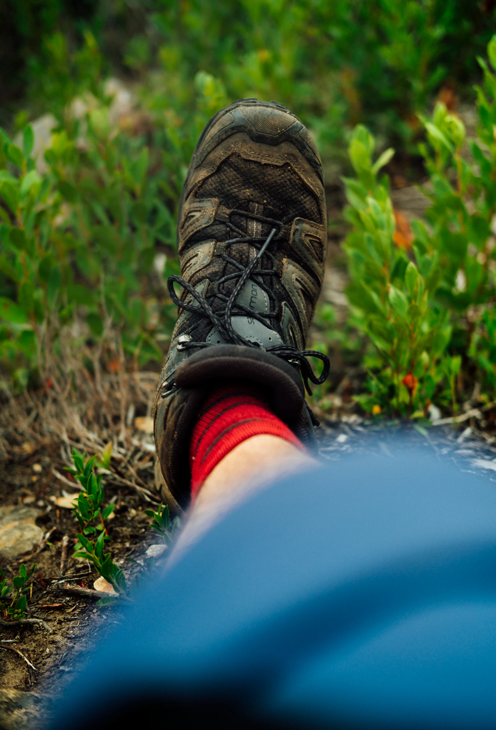 Close-up of a waterproof hiking boot on a muddy countryside trail