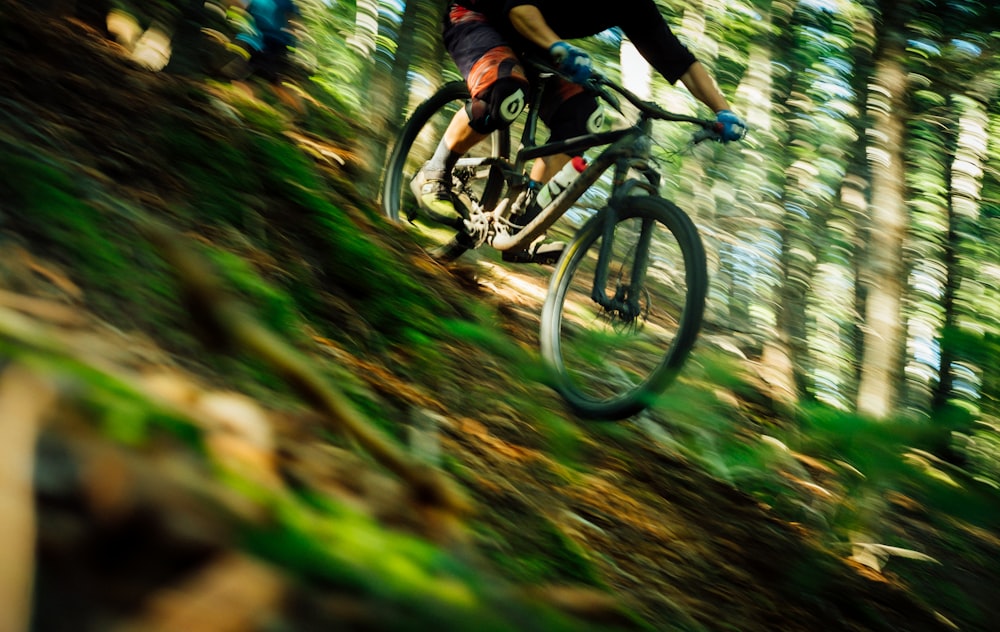 Person, die tagsüber Hardtail-Fahrrad neben Bäumen fährt