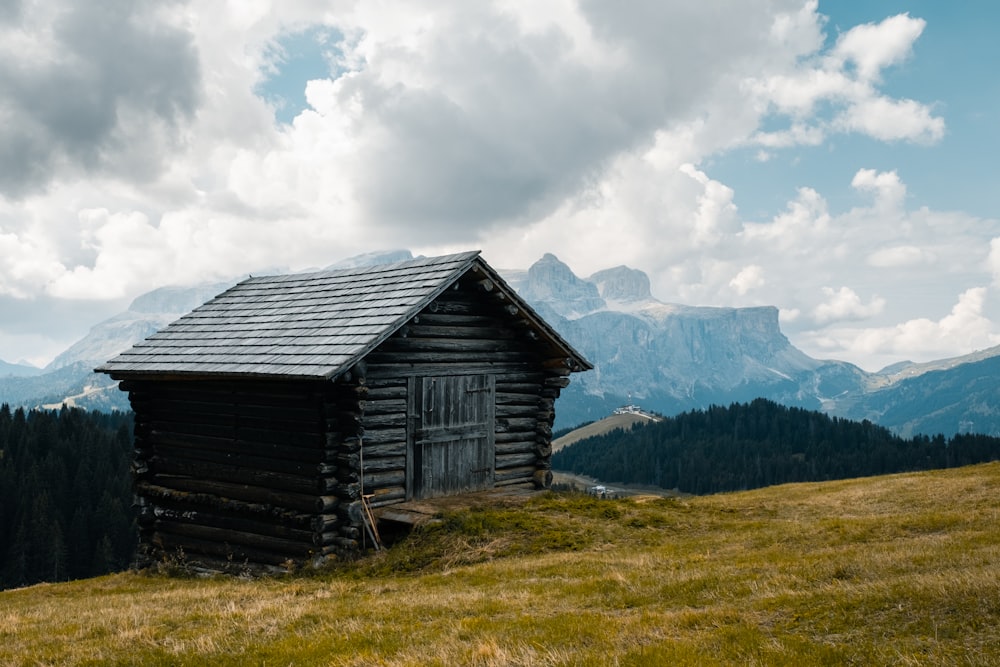 wooden house on grass field on hill under cloudy sky at daytime