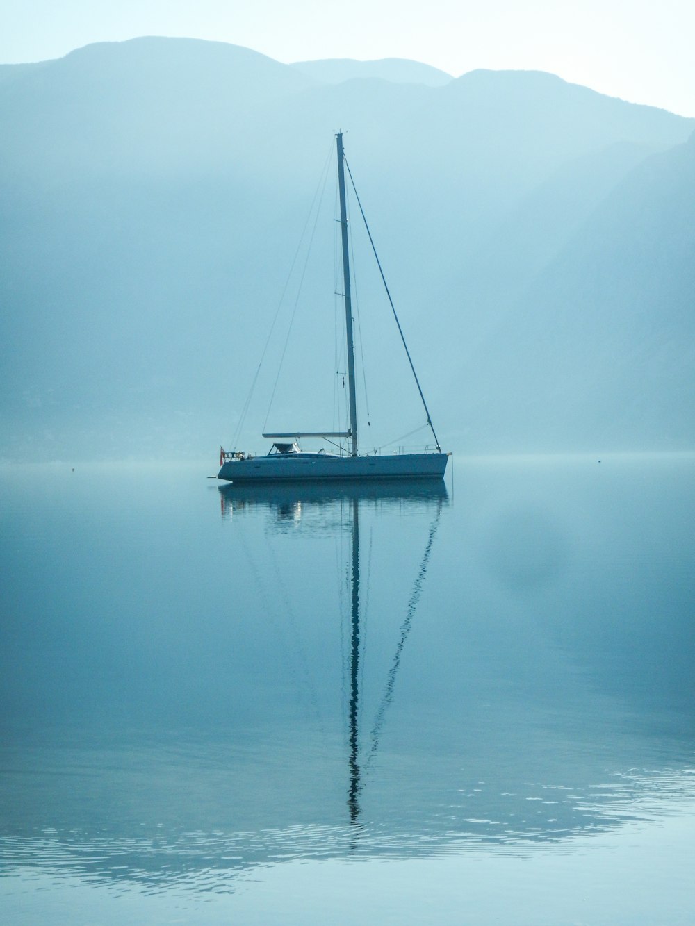 white sailboat sailing on water near mountains