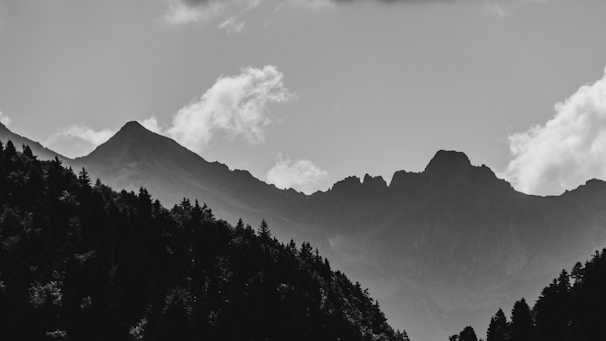 Black and white photo of a misty mountain range at sunrise, showcasing dramatic contrasts and depth.