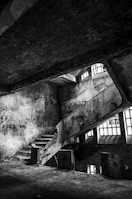 An abandoned urban stairwell glowing faintly with crimson and black hues.
