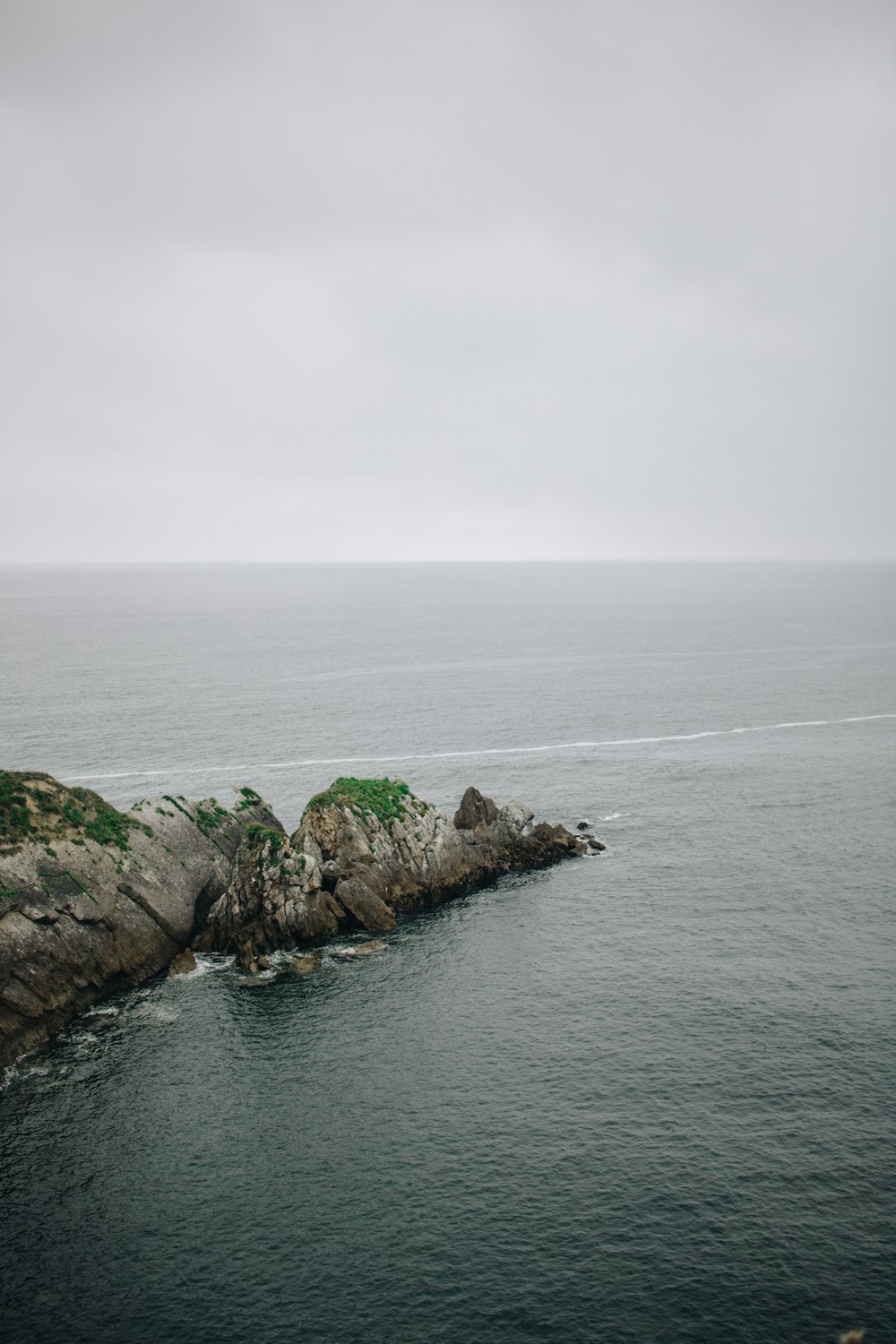 green and gray rock formation surrounded by water during daytime