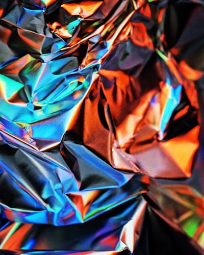 Close-up of vibrant foil rolls in blue, green, red, and gold neatly lined up on a wooden kitchen counter.