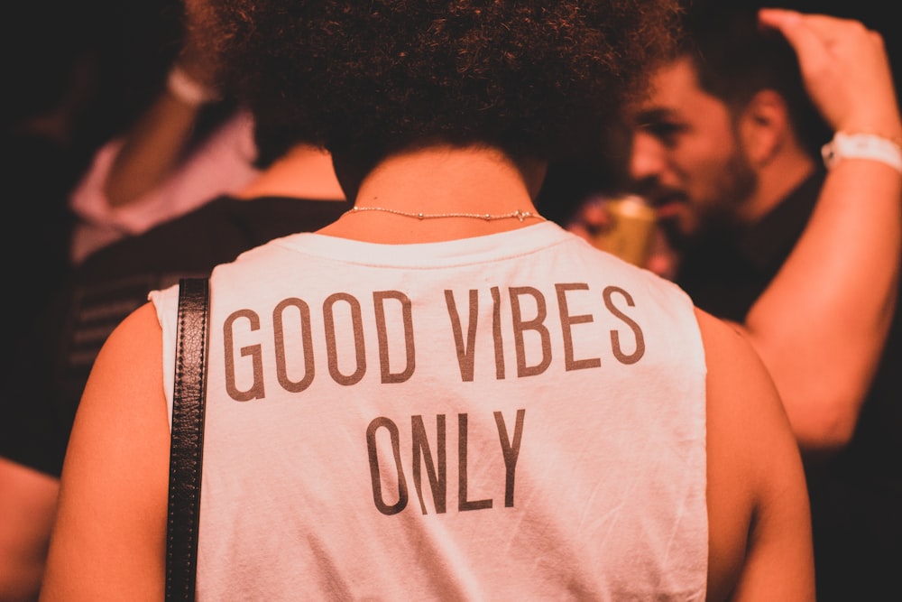 photo of person wearing white and brown good vibes only shirt