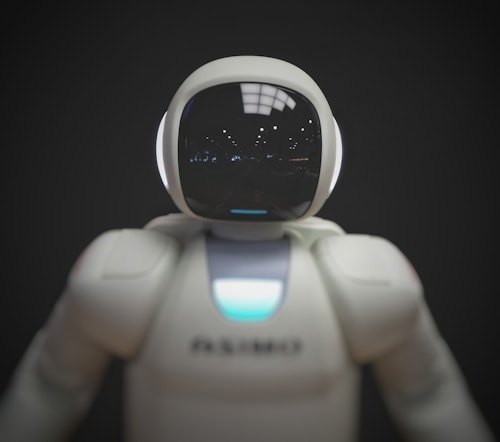 A humanoid robot with a smooth, white exterior and a glossy, reflective helmet-like faceplate. The robot appears to have glowing sensors or lights.