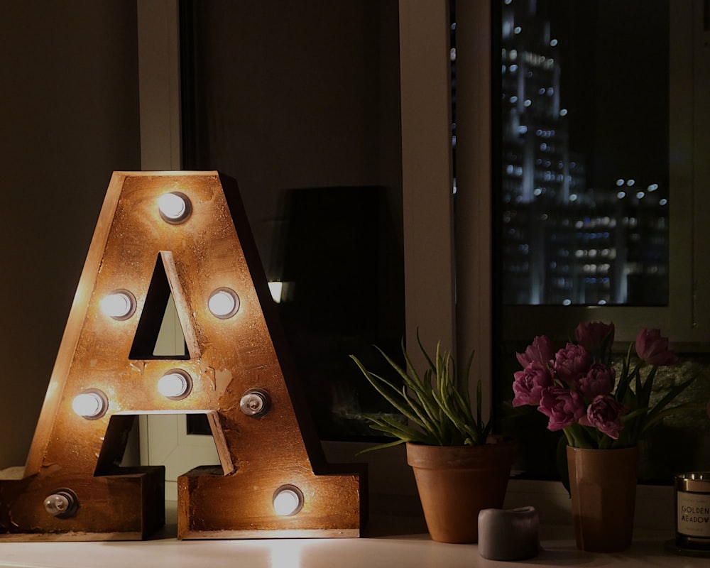 brown wooden A free standing letter near green leaf plant