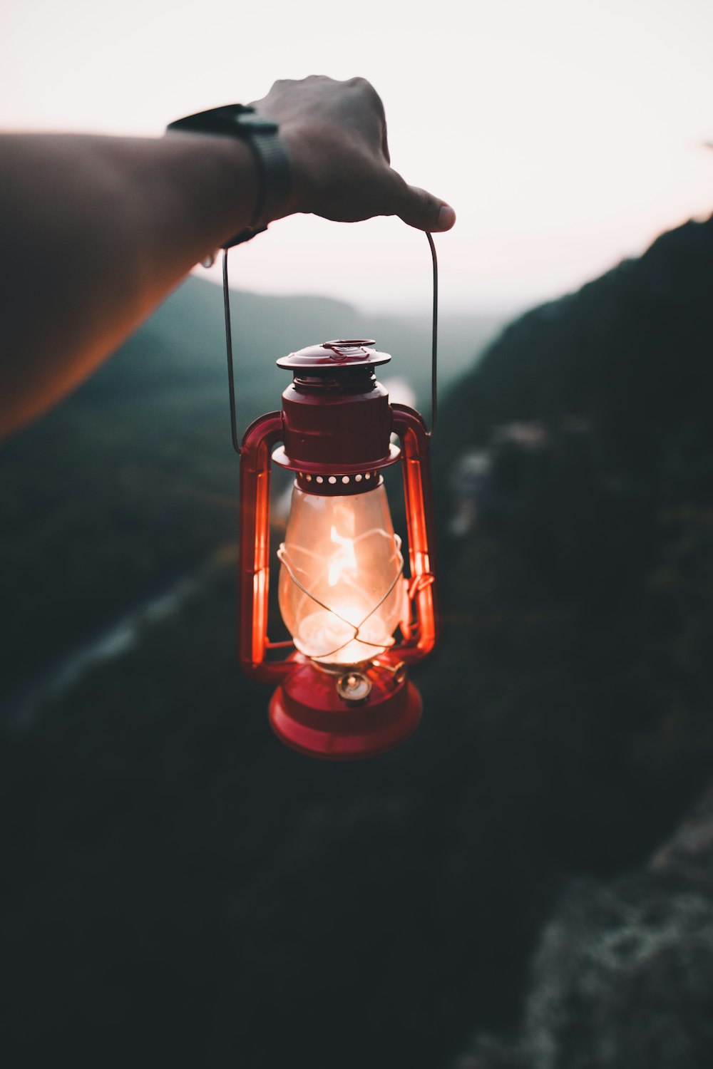 person holding red kerosene lamp