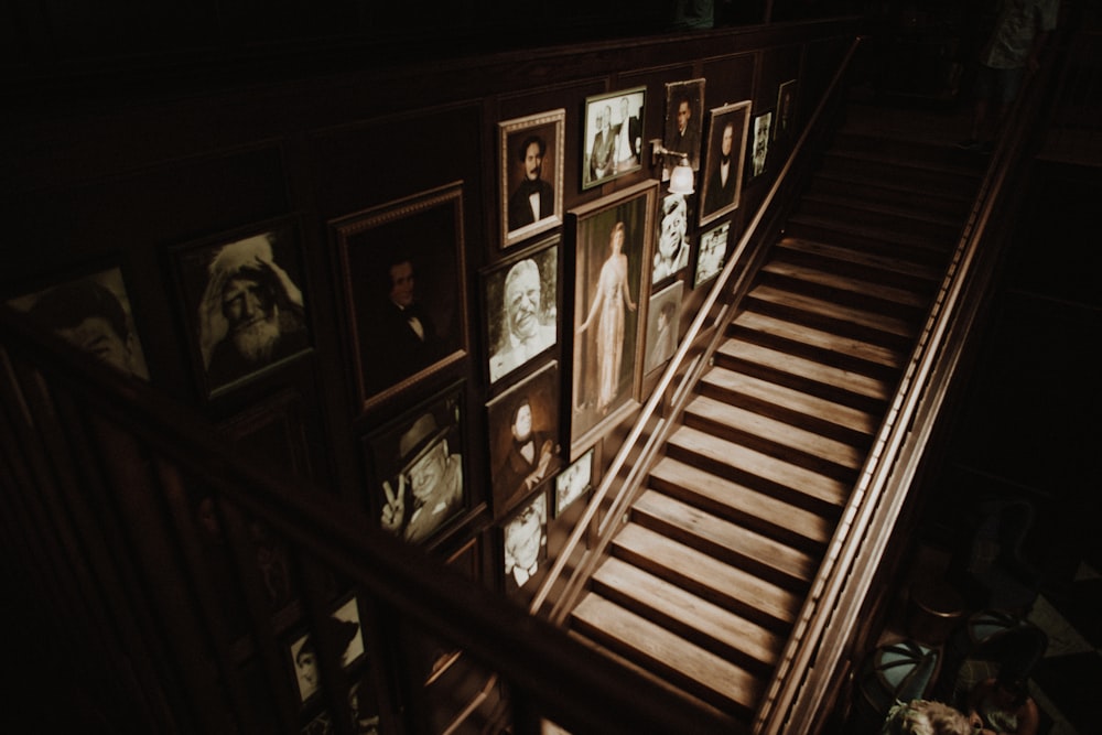 photo frames hanged on wall beside empty brown wooden stairs