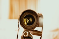 A close-up of a camera lens focusing amid warm studio lights.