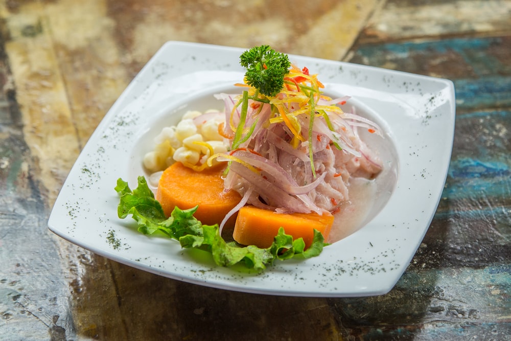 Ensalada de verduras en plato blanco sobre mesa marrón