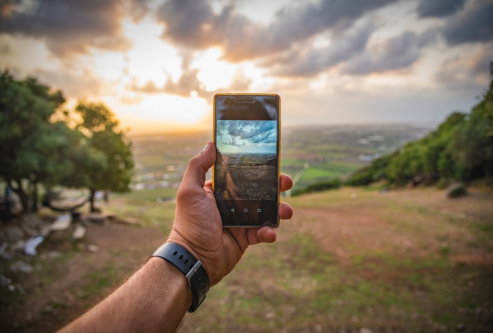 persona sosteniendo un teléfono inteligente Android negro