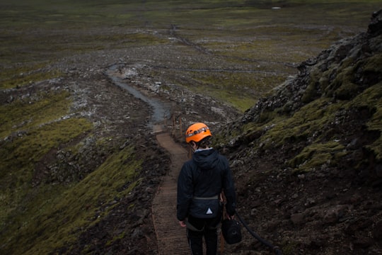 photo of man with helmet standing near mountain slope in Katla volcano Iceland