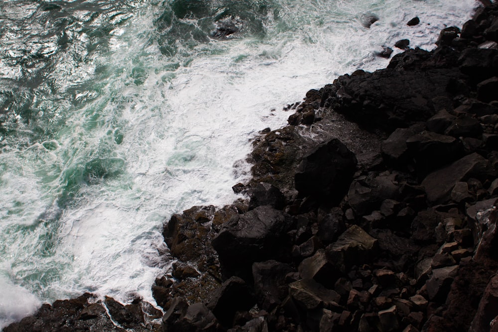 person standing on rocky cliff facing body of water