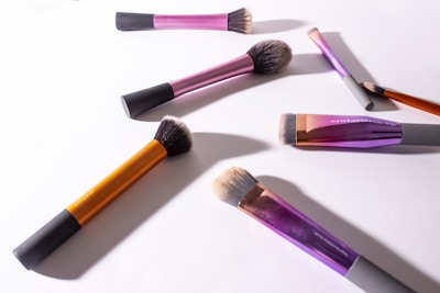 Colorful makeup brushes and palettes spread out on a clean white surface.