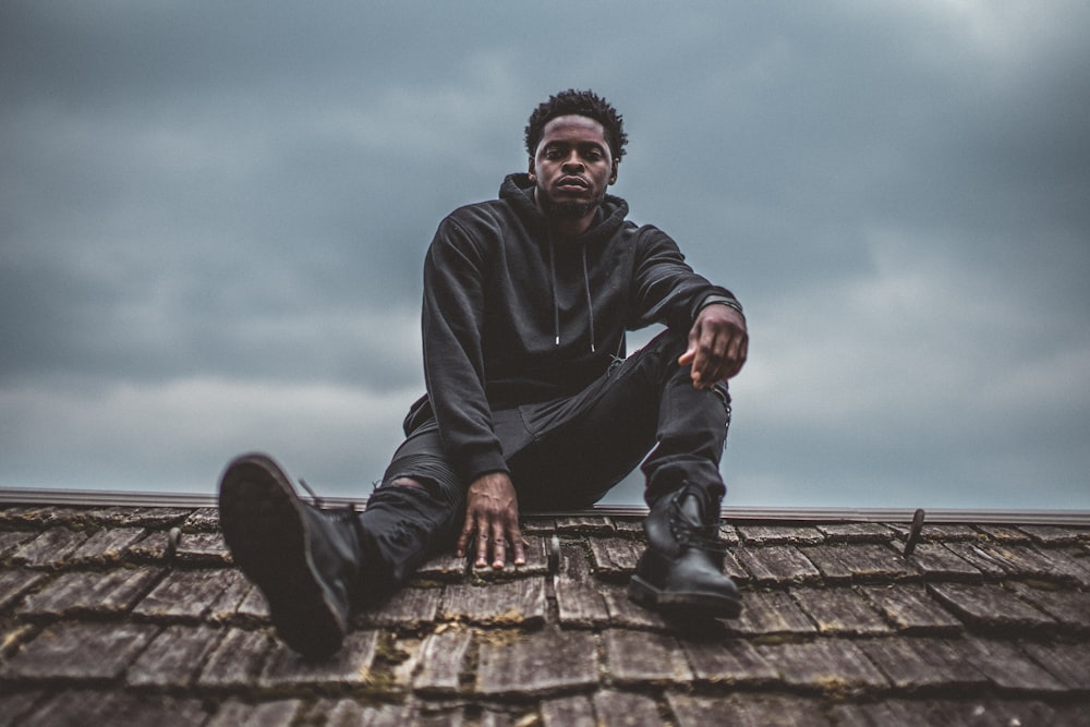 man in black pullover hoodie sitting on roof