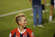 Portrait of a determined footballer smiling confidently with team colors in the background.