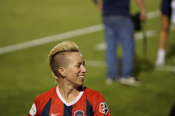 A smiling young fan wearing a justkiting jersey, cheering passionately at a local soccer match.