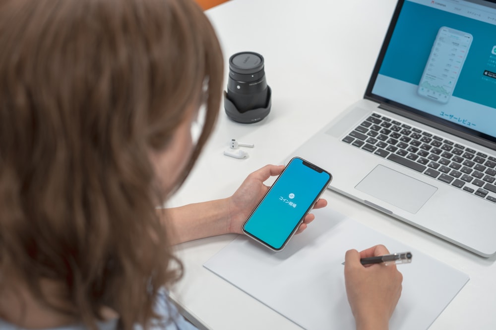 woman holding smartphone while writting