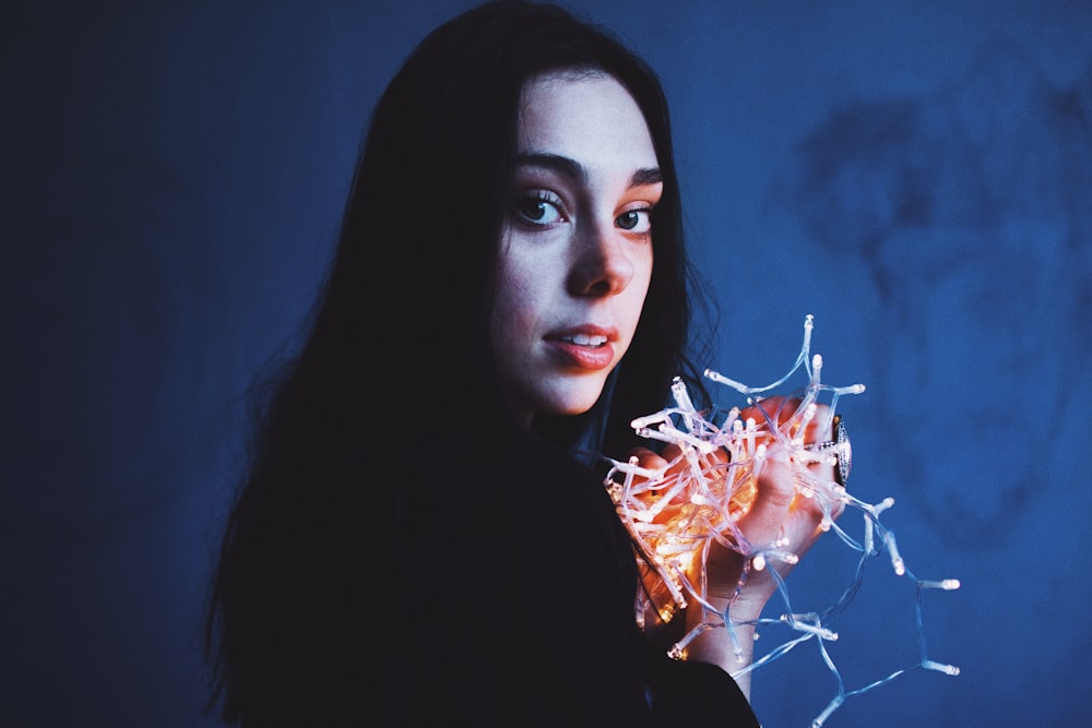 woman holding string light near wall