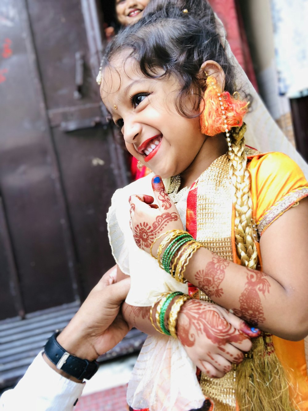 smiling girl wearing gold cap-sleeved dress with red mehndi arm tattoos