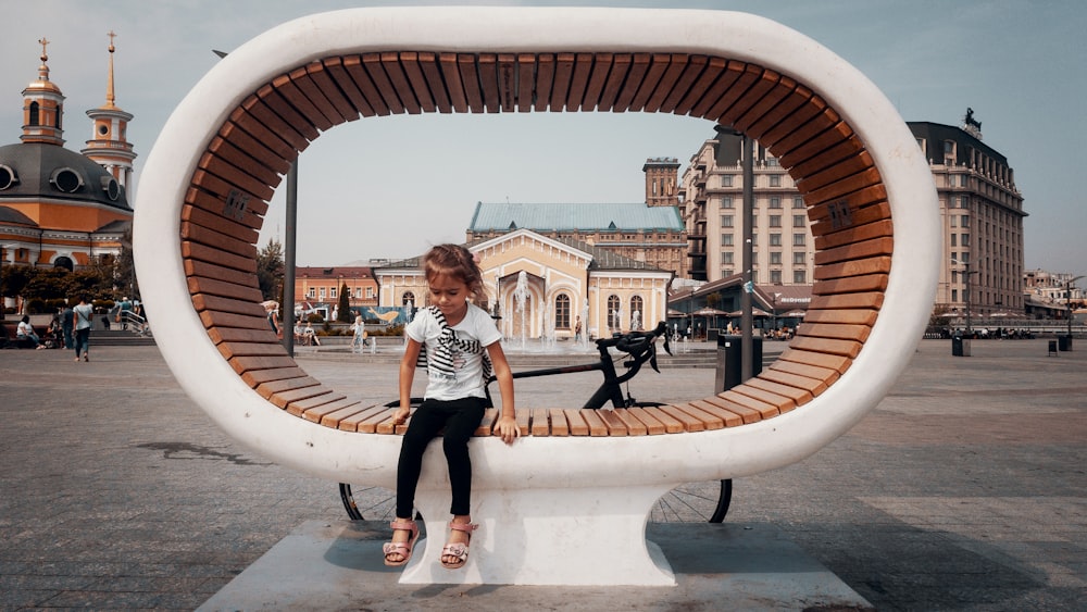 girl wearing gray crew-neck shirt and black leggings sitting on bench