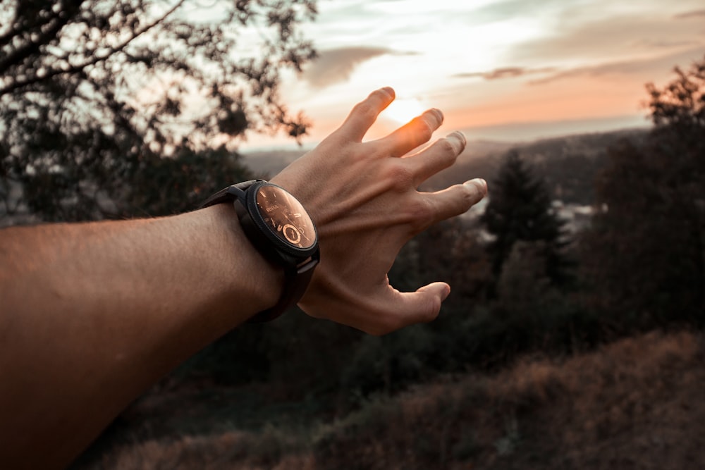 man wearing watch covering sun