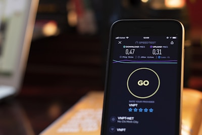 A smartphone screen displaying an internet speed test app, showing download and upload speeds of 0.47 MB/s and 0.31 MB/s respectively. The background is blurred, potentially showing a dim environment with warm lighting.