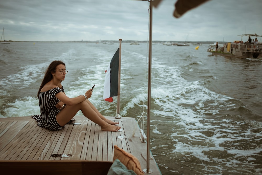 Frau sitzt auf Holzdeck über Gewässer