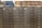 A row of gray metal filing cabinets with drawers, each labeled with small white and black tags. On top of the cabinets, there is a collection of hardbound books arranged in two groups. The books are a mix of blue and brown colors, and they appear to be reference or index volumes.
