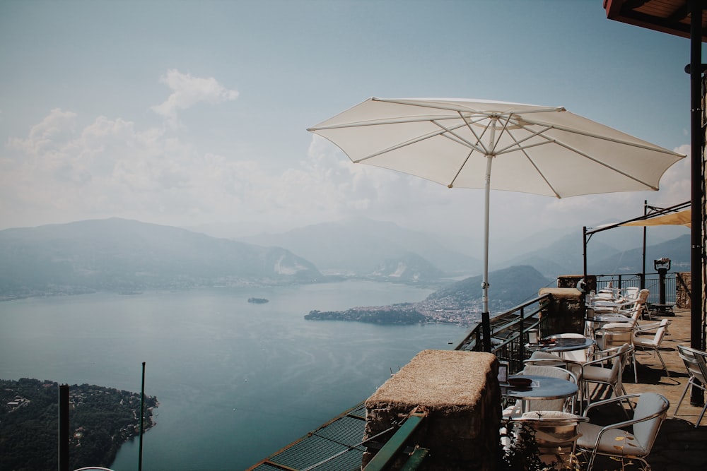 white patio umbrella beside chair during daytime