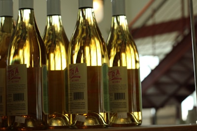 Close-up of three elegant wine bottles displayed on a wooden shelf in a warm light.