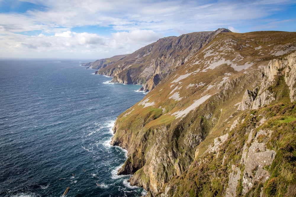 aerial photography of body of water hitting mountain