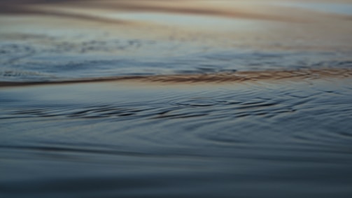 A close-up of delicate ripples on a calm blue sea reflecting the sky.