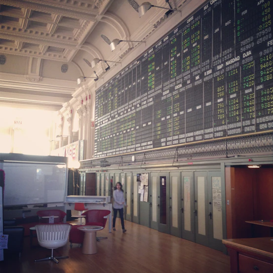 A modern newsroom with multiple screens showing live market data and financial charts.