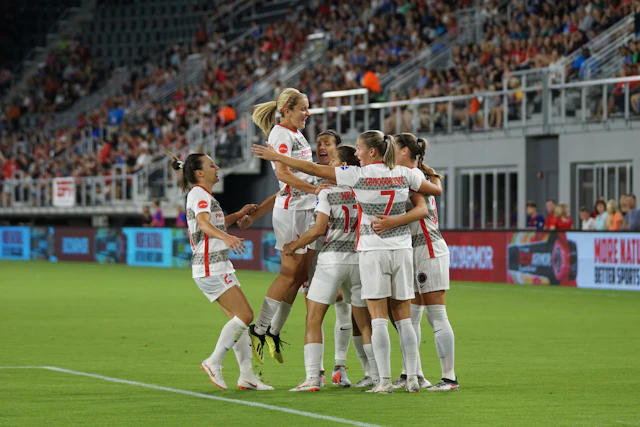 A girls' soccer team posing together on the field